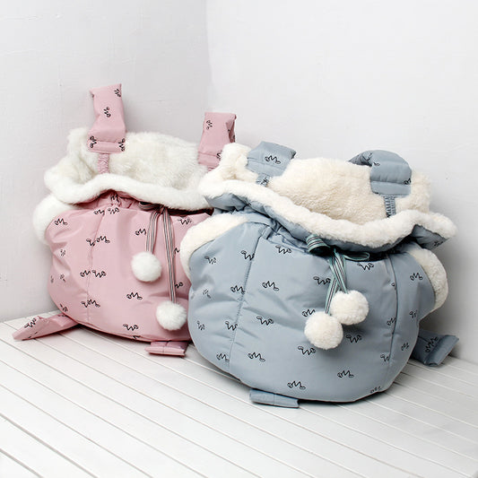 Pink and blue baby bags with white fur lining on a light wooden floor.
