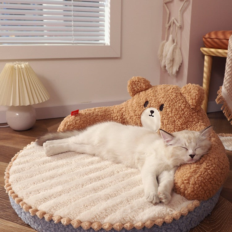 Cat sleeping on a round, plush pet bed with a teddy bear design in a cozy room.