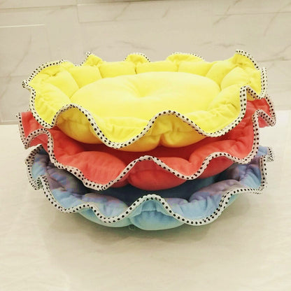Stack of colorful pet beds with ruffled edges on a light background