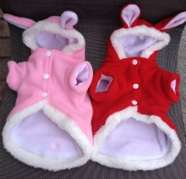 Two pet outfits, one pink and one red, with bunny ears on a dark textured background.