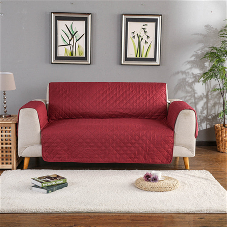 Red sofa cover on a beige sofa in a living room with decorative elements.