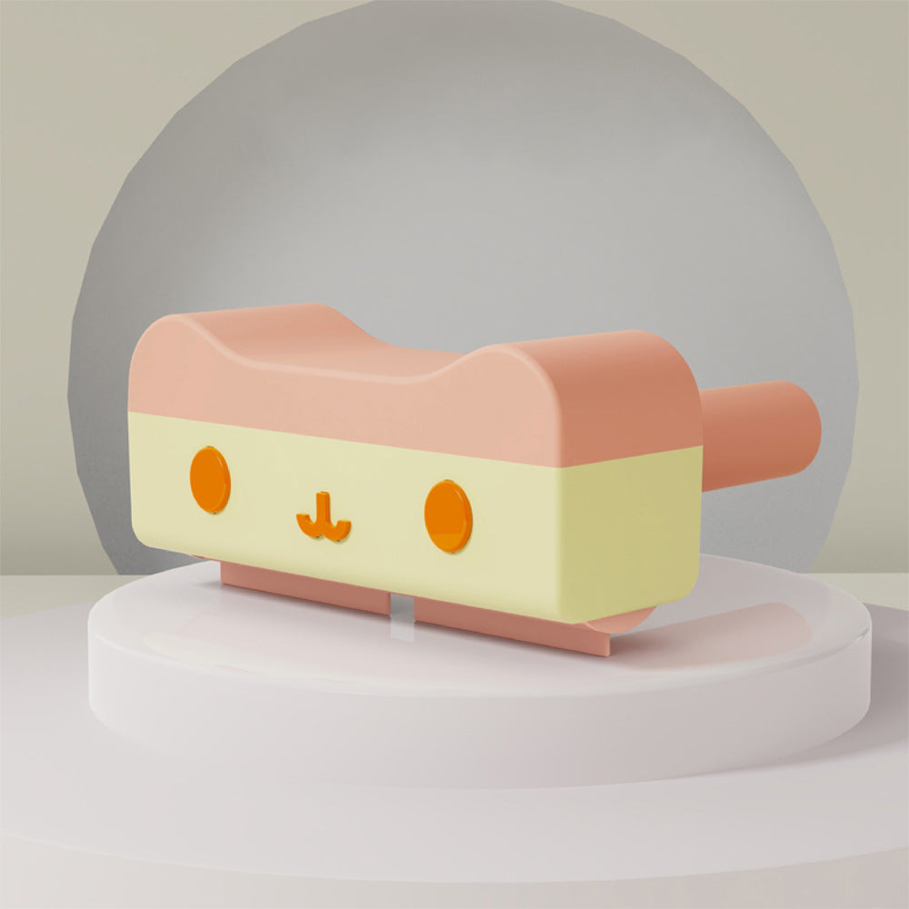 Pink and yellow toy with a face on a white platform against a light gray background