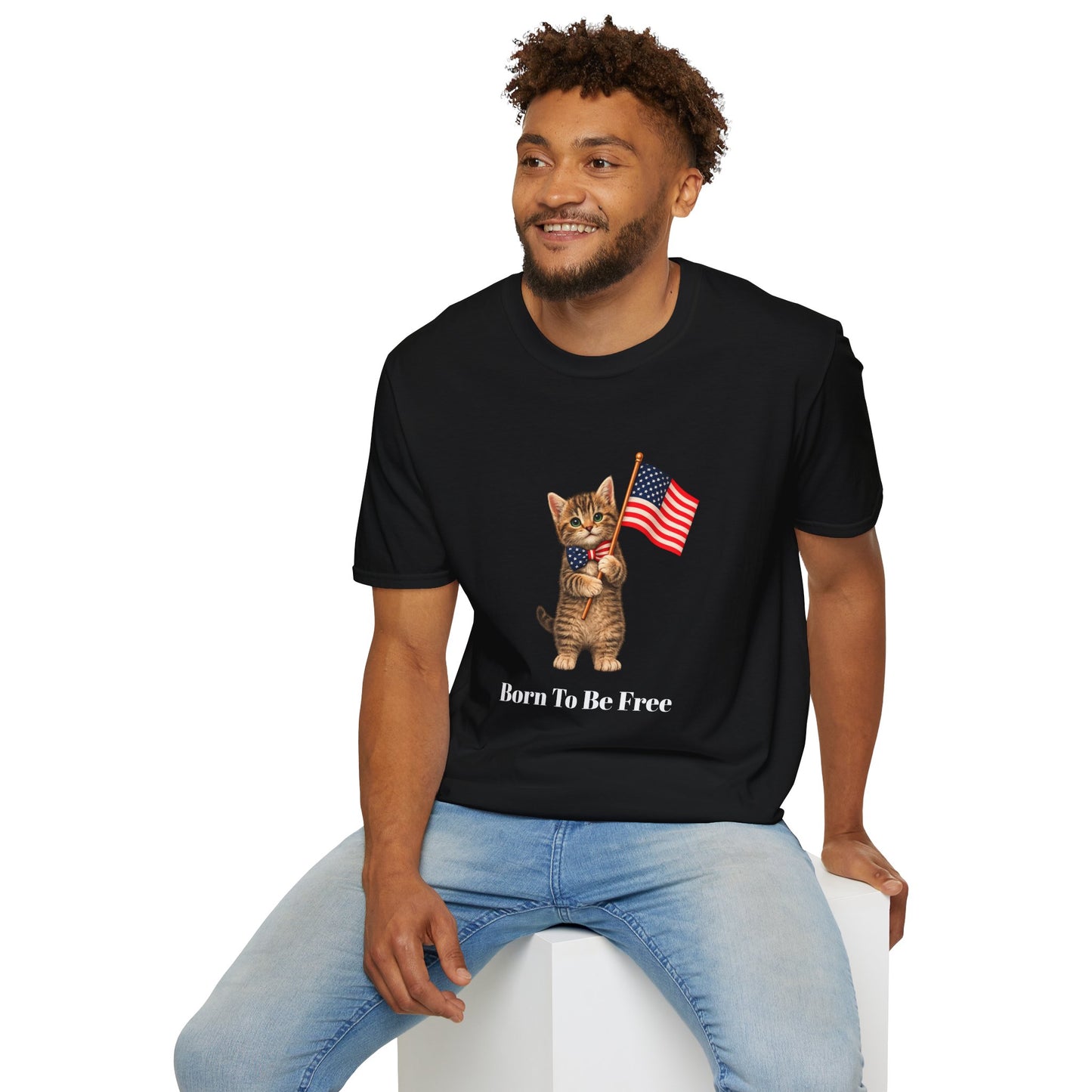 Man wearing a black t-shirt with a graphic and text, sitting on a white stool against a white background.