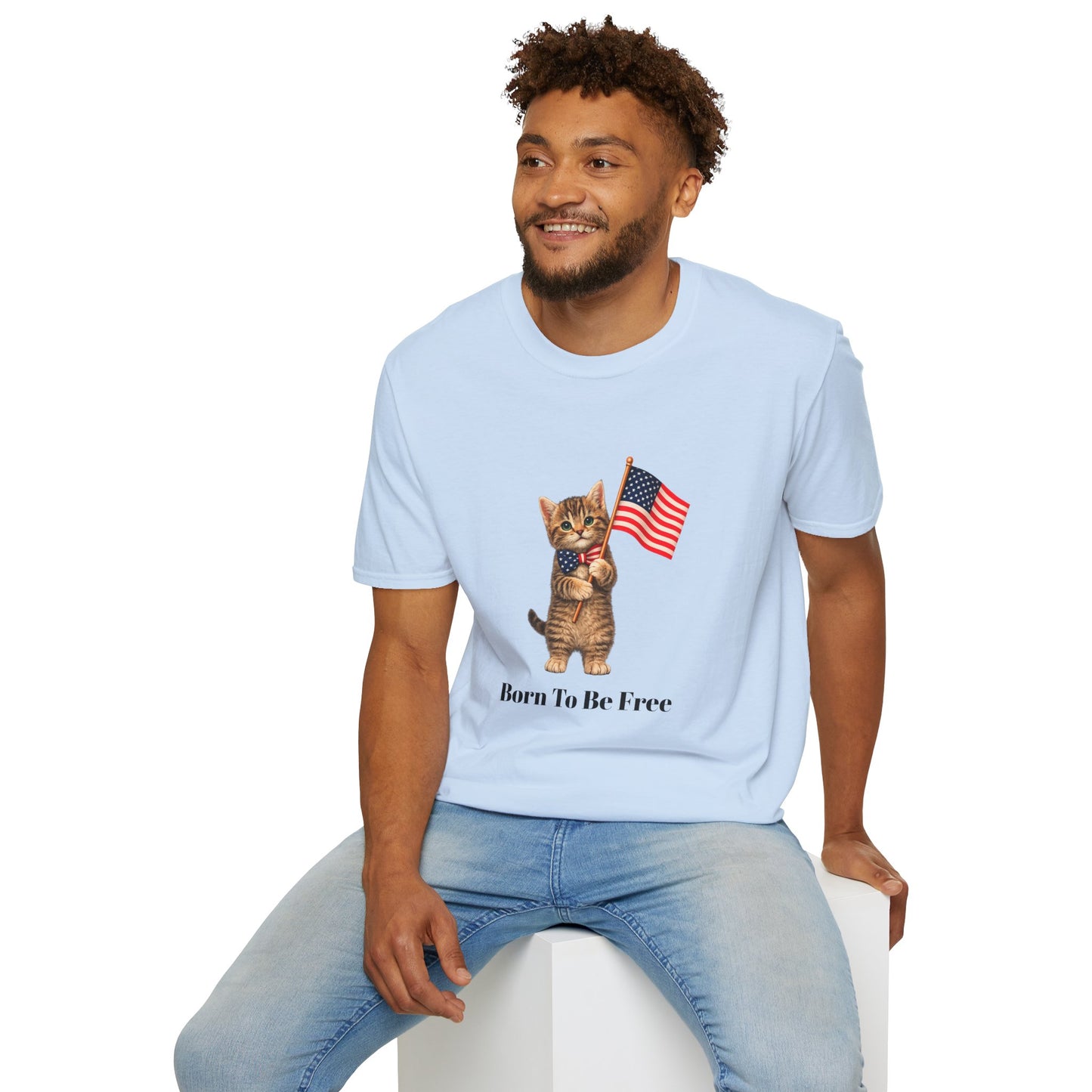 Man wearing a light blue t-shirt with a cat graphic and text, sitting on a white stool.