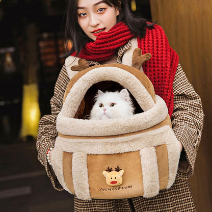 Person holding a cat in a cozy, plush carrier with a reindeer design.