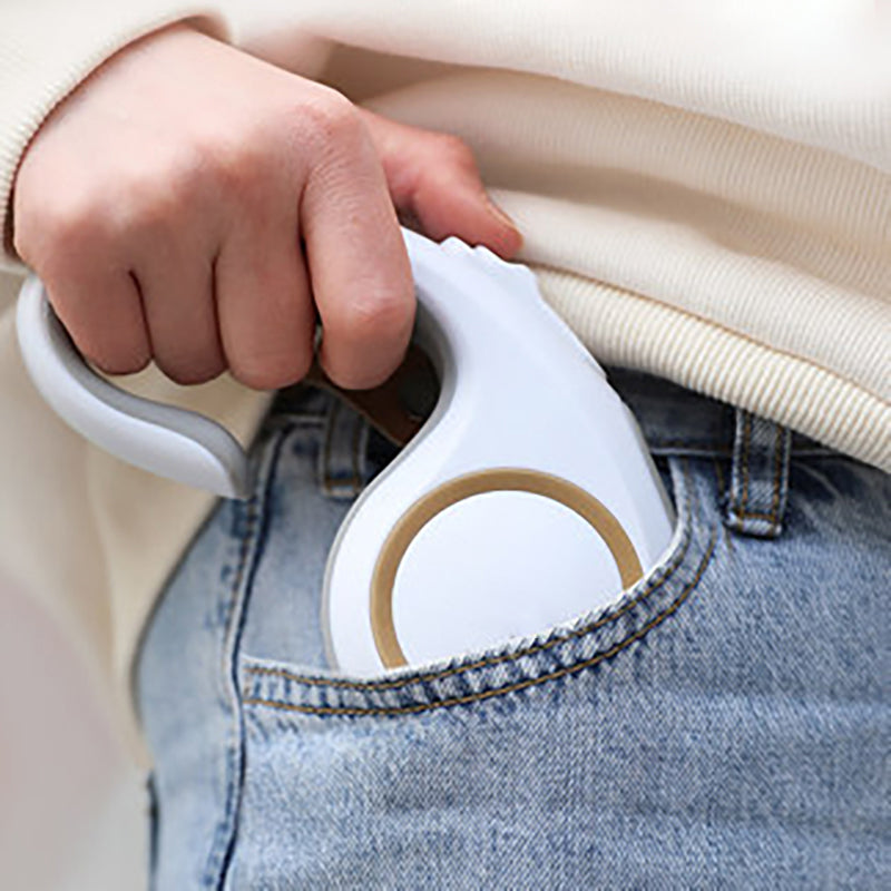 Hand holding a white handheld steamer over a garment with a blurred background