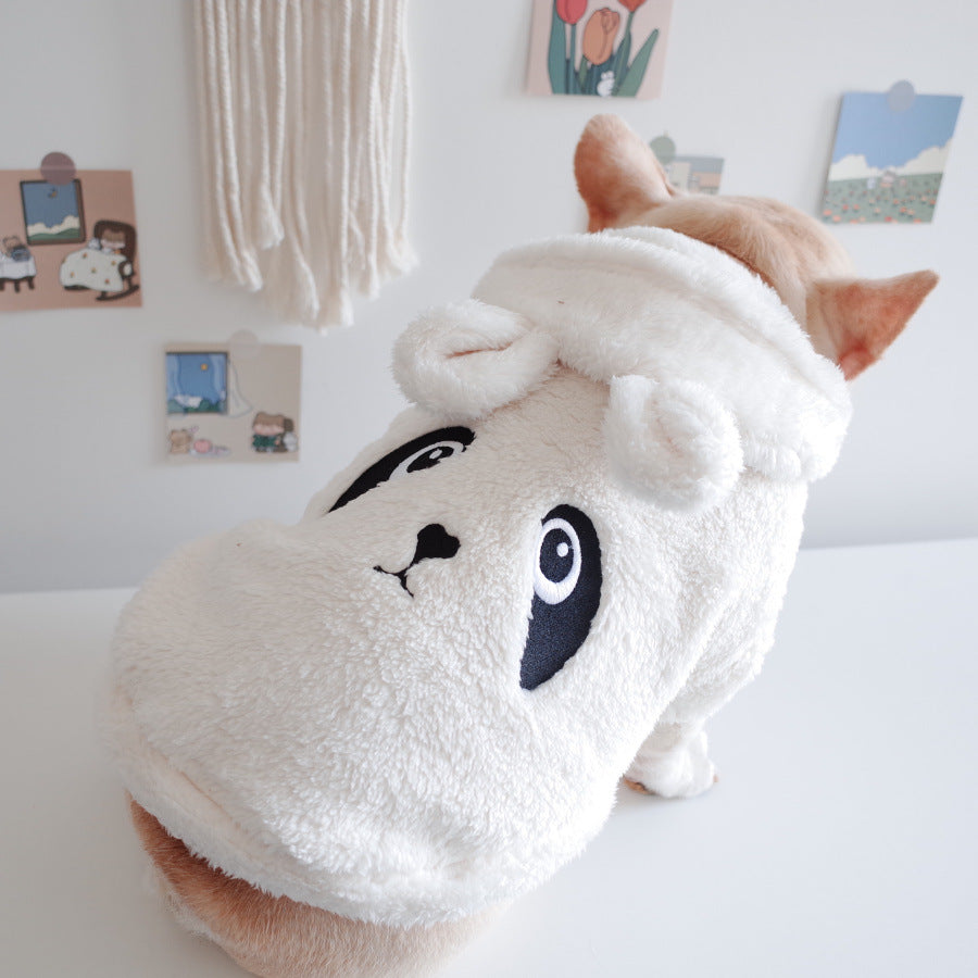 Dog wearing a white hood with cartoon face design on a light-colored surface.
