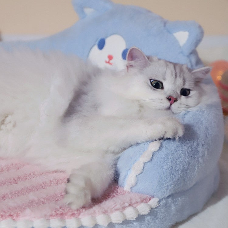 Cat lying on a blue pet bed with a cartoon face