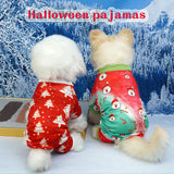 Two dogs wearing red and green Christmas-themed pajamas in front of a snowy landscape.