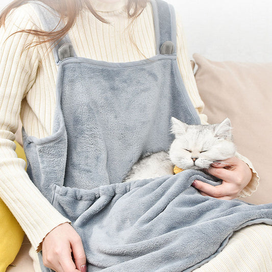 Person holding a white cat wrapped in a gray blanket on a couch.