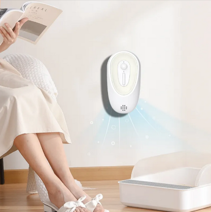 Person sitting on a chair reading a book with a white electronic device on the wall.