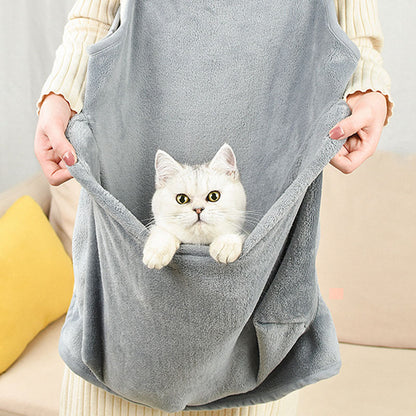 Person holding a gray pet sling with a white cat inside, sitting on a beige couch.