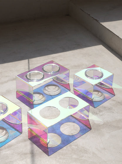 Iridescent geometric candle holders on a neutral background