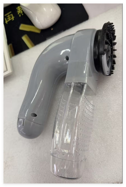 Gray handheld cleaning tool with a black bristle brush on a white surface.