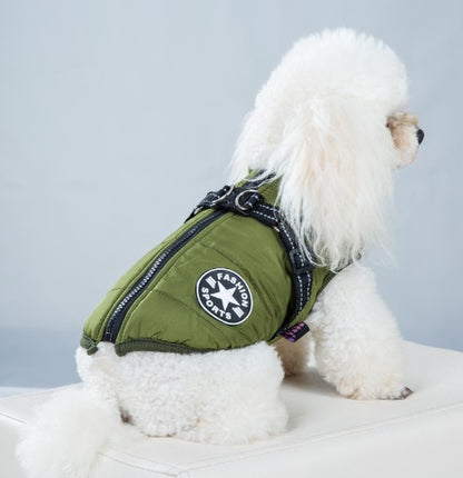 Small white dog wearing a green jacket with a brand logo on a light gray background