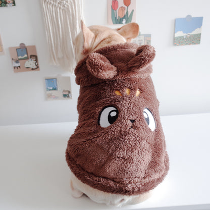 Dog wearing a brown plush costume with cartoon face on a white surface.